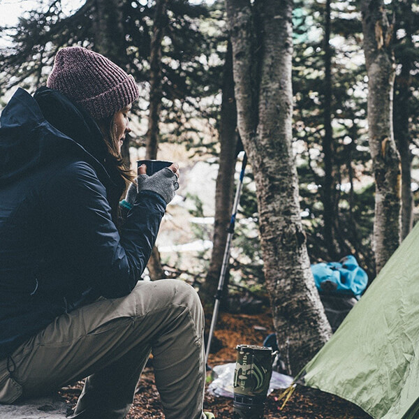 camper drinking coffee outside her tent